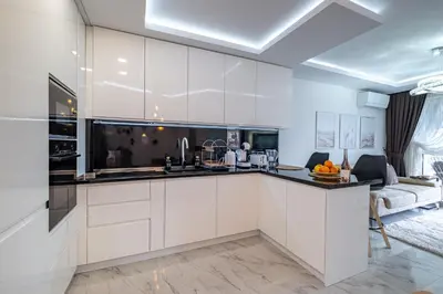 a kitchen with white cabinets and a living room at Boutique 1 bedroom apartment with Private Parking and Port View in Varna City