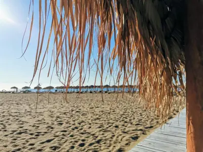 a beach with a straw umbrella on the sand at Kambani 1 Apartment in Sveti Vlas