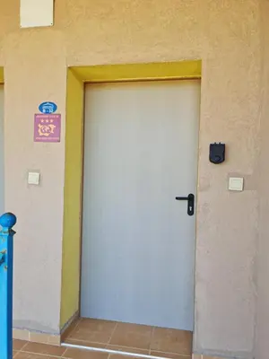 a white garage door with a sign on a wall at Апартаменти за гости ГАРДЪН БИЙЧ in Chernomorets
