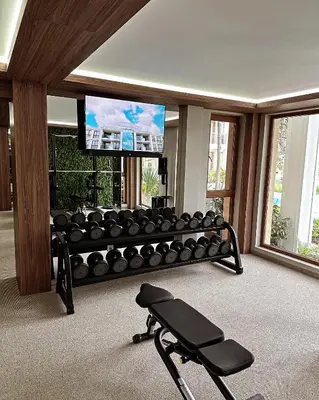 a room with a gym with a bench and a flat screen tv at Tranquilo Escapes in Sunny Beach