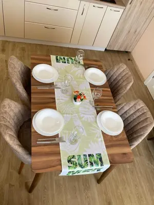 a wooden table with white plates and wine glasses at Garmanovi Apartment in Sozopol, with free parking in Sozopol