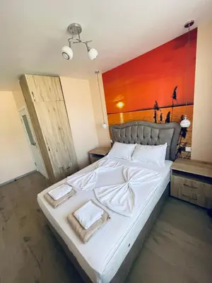 a bedroom with a large white bed with a red wall at Sunset studio in Sozopol, with free parking in Sozopol