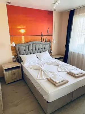 a bed in a bedroom with a painting on the wall at Sunset studio in Sozopol, with free parking in Sozopol
