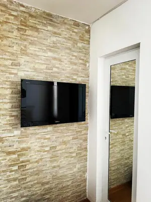 a flat screen tv mounted on a brick wall at Стаи за гости Гергана град Созопол in Sozopol