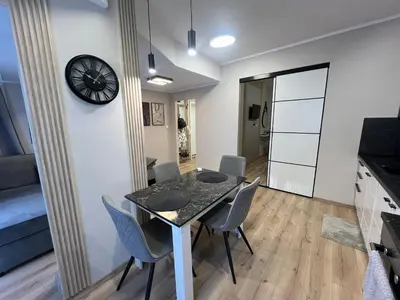 a dining room with a table and chairs and a clock at Varna central apartment with parking for normal to middle sized cars in Varna City