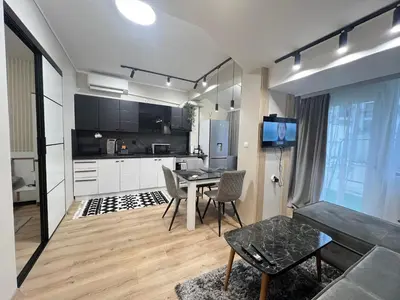 a living room with a table and a kitchen at Varna central apartment with parking for normal to middle sized cars in Varna City
