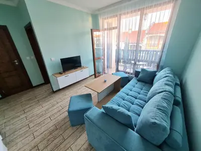 a living room with a blue couch and a large window at Апартаменти в Комплекс Трявна Бийч in Sveti Vlas