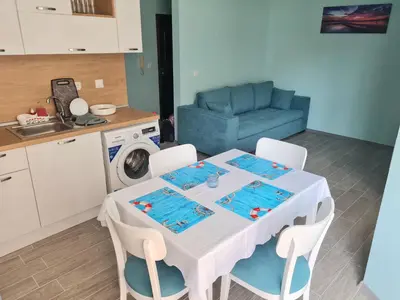 a kitchen with a table with chairs and a blue couch at Апартаменти в Комплекс Трявна Бийч in Sveti Vlas
