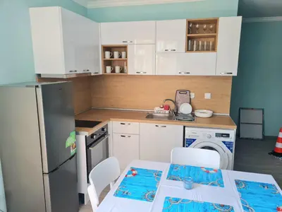 a kitchen with a refrigerator and a table and chairs at Апартаменти в Комплекс Трявна Бийч in Sveti Vlas