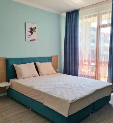 a bedroom with a large bed with a window at Апартаменти в Комплекс Трявна Бийч in Sveti Vlas