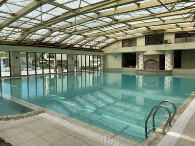 a large swimming pool with blue water in a building at Apartment in Long Beach in Shkorpilovtsi