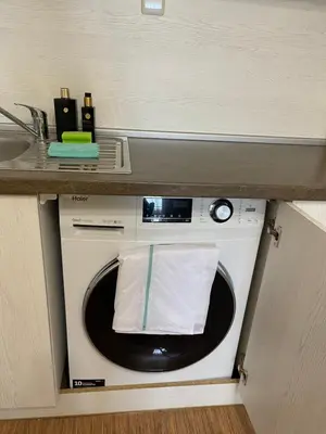 a washing machine under a counter with a sink at Apartment in Long Beach in Shkorpilovtsi