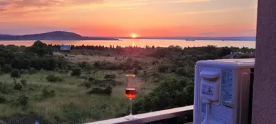 a glass of wine sitting on a balcony watching the sunset at Vila Mihnevi in Chernomorets
