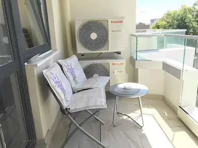 a chair and a table in a room with a window at HOT Main Square Newly Built Modern Apartment in Burgas City