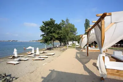 a beach with lounge chairs and umbrellas and the water at 2 Apartment Verano Del Mar Sozopol in Sozopol