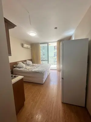 a bedroom with a white bed and a refrigerator at Apart Hotel Avalon in Sunny Beach