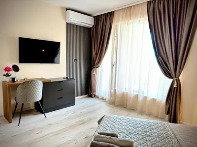 a bedroom with a bed and a desk and a window at South Bay Luxury Apartment in Varna City