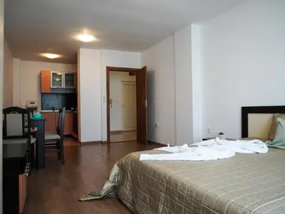 a bedroom with a bed and a table and a kitchen at Jolly apartments in Nesebar