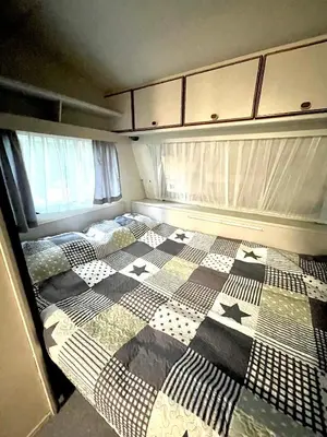 a small bedroom with a bed with a checkered blanket at Каравана Безвремие in Chernomorets