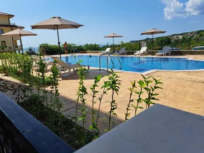 a swimming pool with chairs and umbrellas at Sun Holidays Byala in Byala