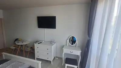 a bedroom with a dresser and a tv on the wall at Beachfront one bedroom apartment DIAMOND BEACH Burgas Sarafovo Студио в Diamond beach Сарафово in Burgas City
