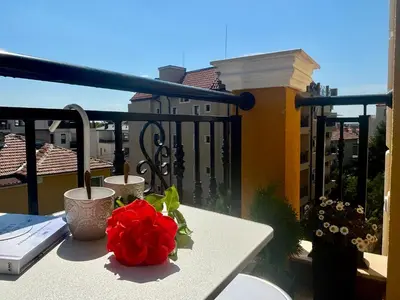 a table with a red rose on a balcony at Triumph apartment in Burgas City