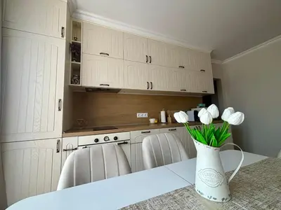 a kitchen with white cabinets and white flowers in a vase at Triumph apartment in Burgas City