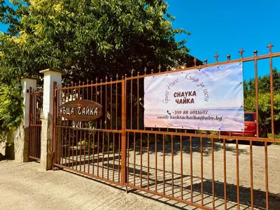 a gate with a sign on it next to a tree at Къща за Гости Чайка in Byala