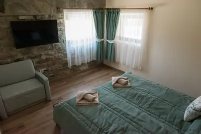 a bedroom with a bed and a chair and a television at Къщи за гости Стара Голица in Golitsa