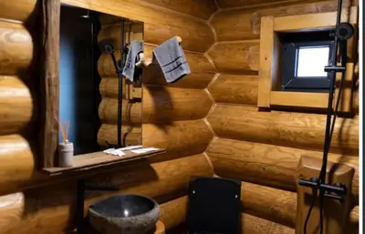 a bathroom with a wooden wall with a tub at Къщи за гости Стара Голица in Golitsa