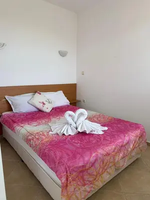 a bed with pink sheets and white towels on it at апартамент под наем виа понтика in Sozopol