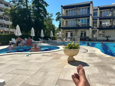 a person laying on a patio next to a swimming pool at Studio Dream Мечта in Sunny Beach