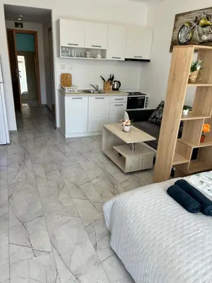 a kitchen and living room with white cabinets and a bed at Studio Dream Мечта in Sunny Beach