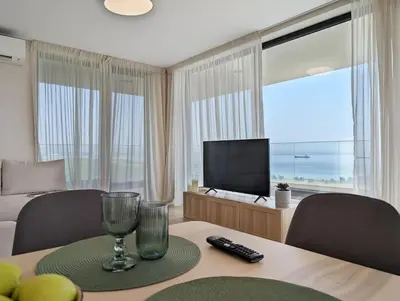 a living room with a table with a television and a room with a tableablish at Foros Apartment in Kraymorie