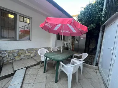 a green table and chairs with a red umbrella at Varna Central Sea Apartment in Varna City