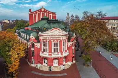 a large red building with a green roof at Varna Central Sea Apartment in Varna City