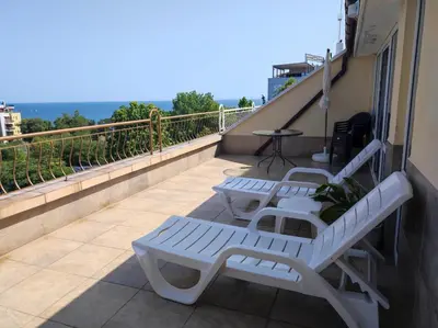 a balcony with three white benches on a building at Апартамент с уникална панорама Несебър in Nesebar