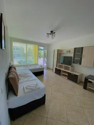 a large room with a bed and a television at Guest House Ropotamo in Primorsko