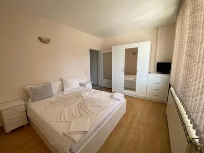 a bedroom with a large white bed and a mirror at Guest House Ropotamo in Primorsko