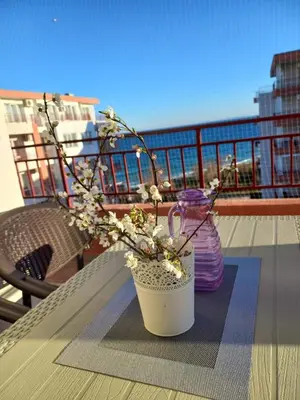 a vase with flowers on a table on a balcony at Riviera Fort Beach Apartment in Ravda