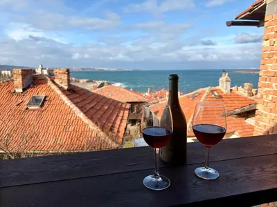 two glasses of wine sitting on a table with a bottle of wine at Arthotel Oscar I Sozopol in Sozopol