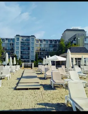 a group of lounge chairs and umbrellas on a beach at Private room Festa Pomorie in Pomorie