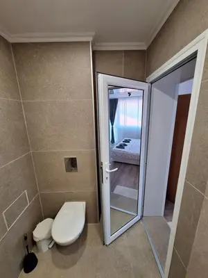 a bathroom with a toilet and a glass door at Manolovi Guest House in Obzor