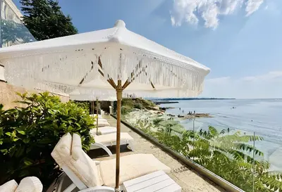 a group of chairs and an umbrella on a beach at Santa Maria Luxury Suits in Ravda