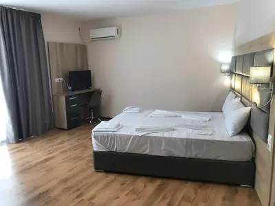 a hotel room with a bed and a television at Marina Beach Apartments Pomorie in Pomorie