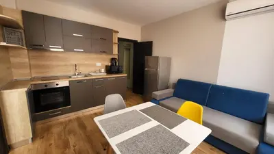 a kitchen with a table and a blue couch in a room at Marina Bay Apartmant in Pomorie