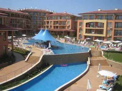 a swimming pool with a blue umbrella and some buildings at Panorama Dreams Apartment in Sveti Vlas