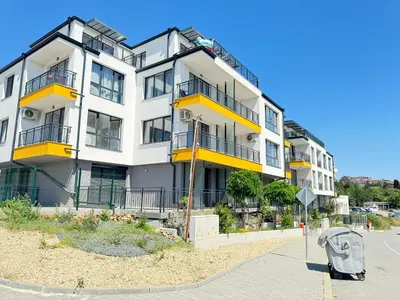 a large white building with yellow balconies on a street at Deco Fusion in Sozopol