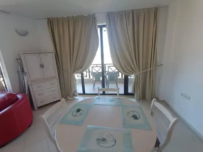a white table and chairs in a room with a window at Oasis Beach 2 bedroom apartment in Lozenets