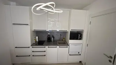 a kitchen with white cabinets and a chandelier at Polar Star 106 B in Saint Vlas in Sveti Vlas